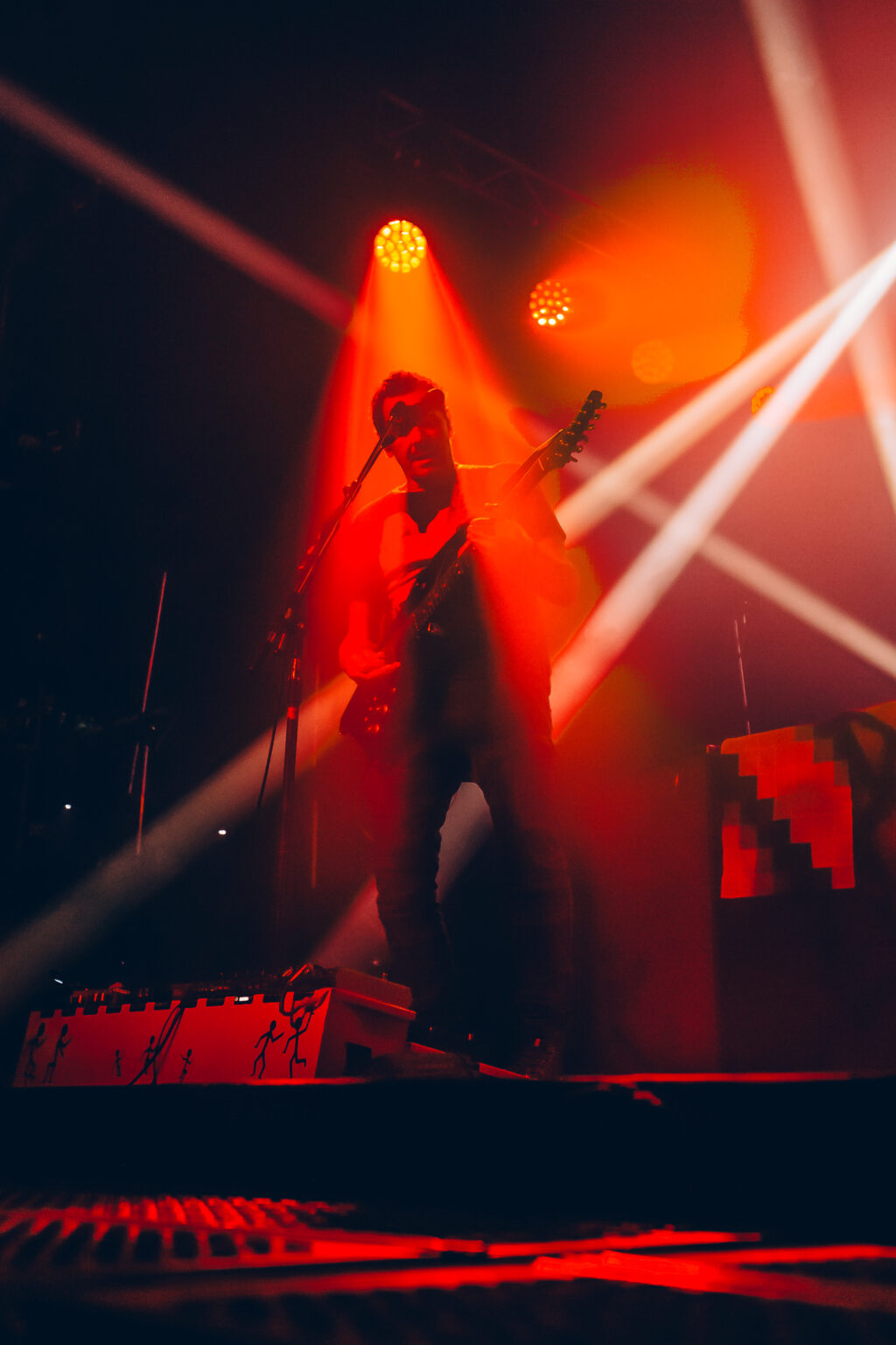 Singer at the microphone in red and orange light — Divididos at Estadio Obras Sanitarias, Buenos Aires, 19 January 2024. Photographed by Anita Almaraz.