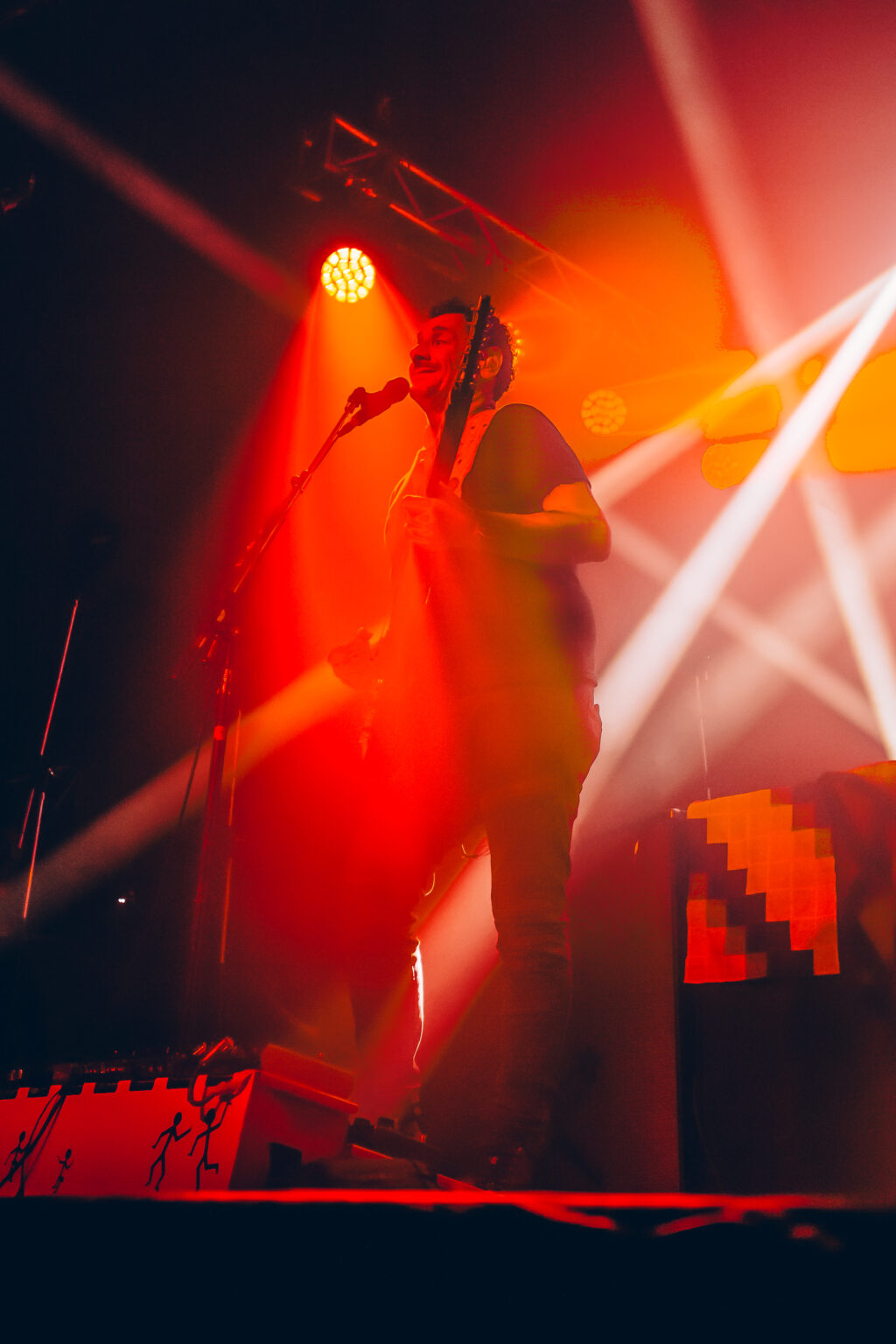 Singer at the microphone with white beams crossing the stage — Divididos at Estadio Obras Sanitarias, Buenos Aires, 19 January 2024. Photographed by Anita Almaraz.