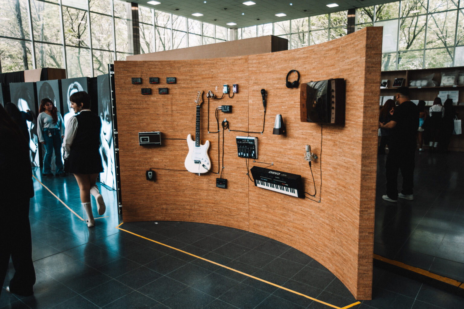 The curved wooden display wall in the exhibition at the BTS POP-UP: ARIRANG IN BUENOS AIRES, Centro de Convenciones Dr. Arturo Frondizi, Vicente Lopez, 2026 — photographed by Anita Almaraz for K-HipHop Argentina