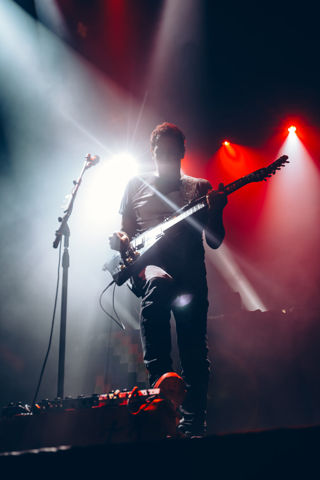 Guitarist with the guitar raised in white light — Divididos at Estadio Obras Sanitarias, Buenos Aires, 19 January 2024. Photographed by Anita Almaraz.