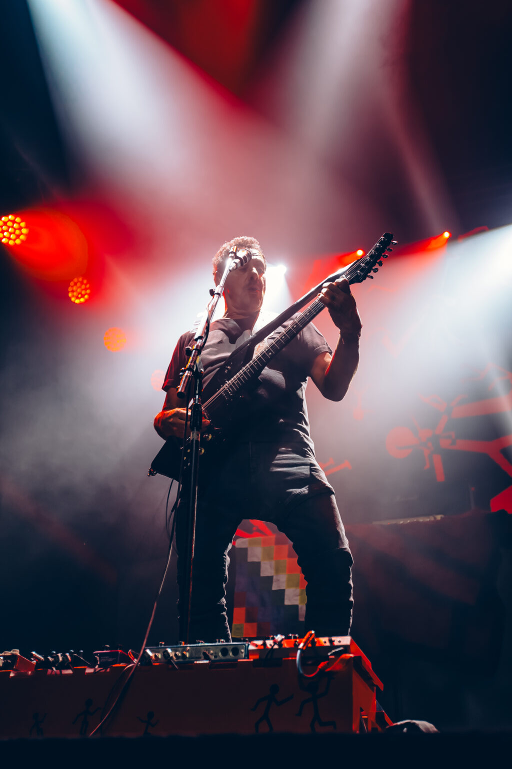 Guitarist against red and white beams — Divididos at Estadio Obras Sanitarias, Buenos Aires, 19 January 2024. Photographed by Anita Almaraz.