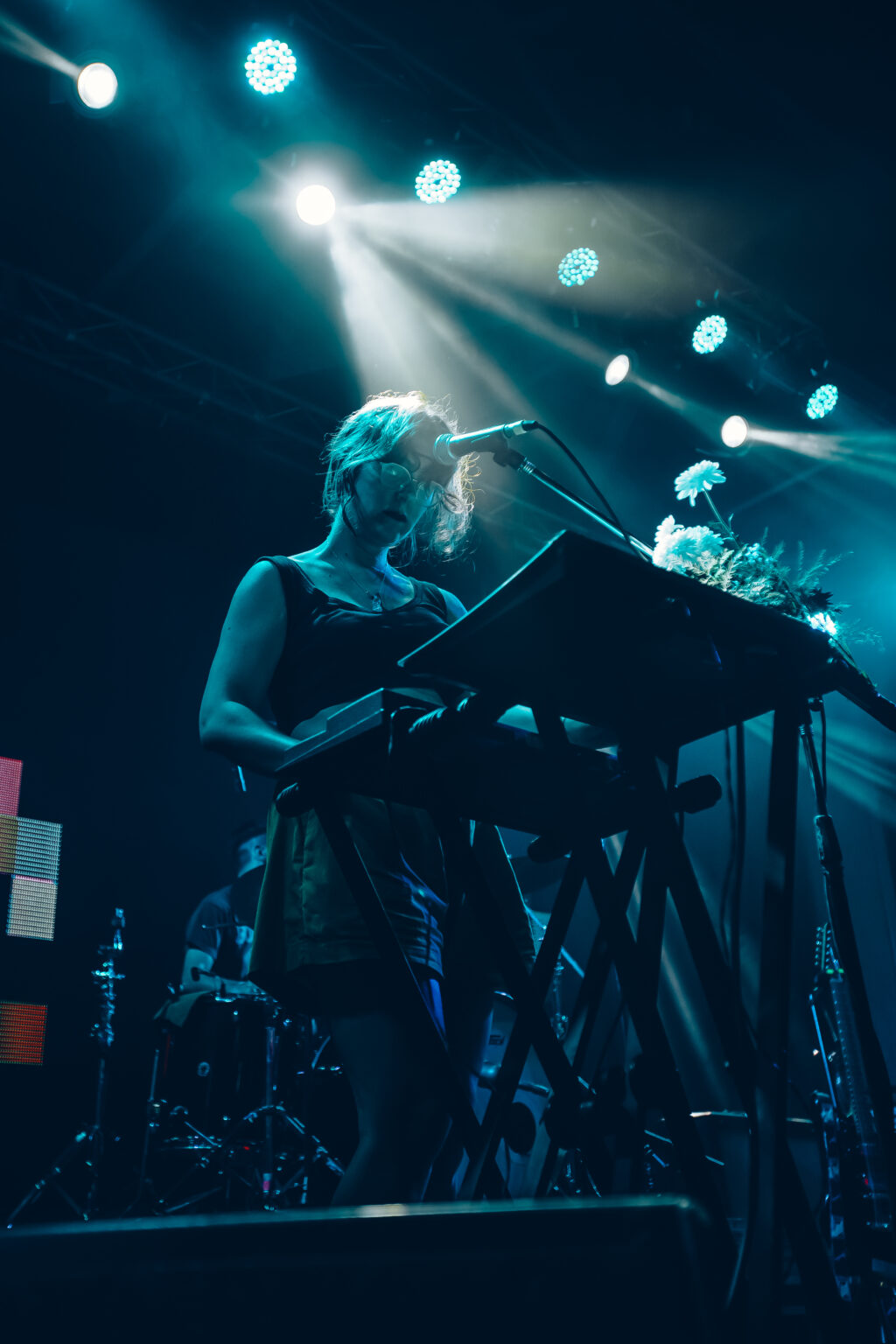 A keyboard player backlit behind a microphone stand wrapped in flowers &mdash; FestiLaptra at Ciudad Cultural Konex, Buenos Aires, 17 February 2024. Photographed by Anita Almaraz.