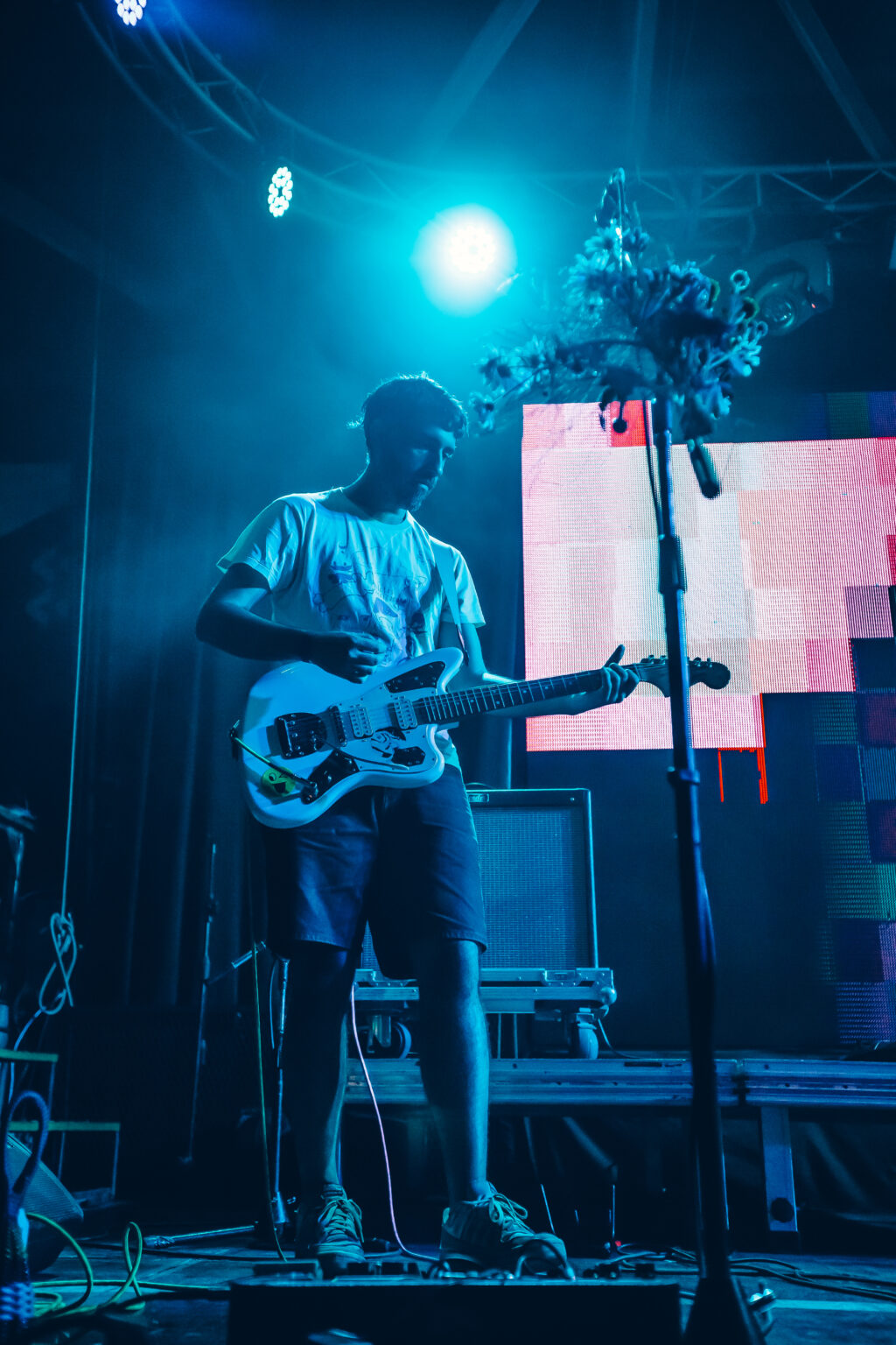 A bass player in blue light, the pixel screen glowing behind him &mdash; FestiLaptra at Ciudad Cultural Konex, Buenos Aires, 17 February 2024. Photographed by Anita Almaraz.