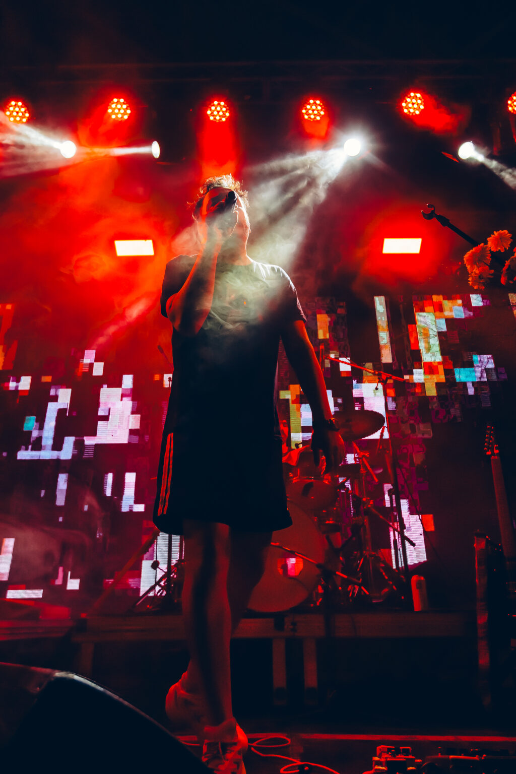 A singer seen from behind, facing the red lights and the crowd &mdash; FestiLaptra at Ciudad Cultural Konex, Buenos Aires, 17 February 2024. Photographed by Anita Almaraz.