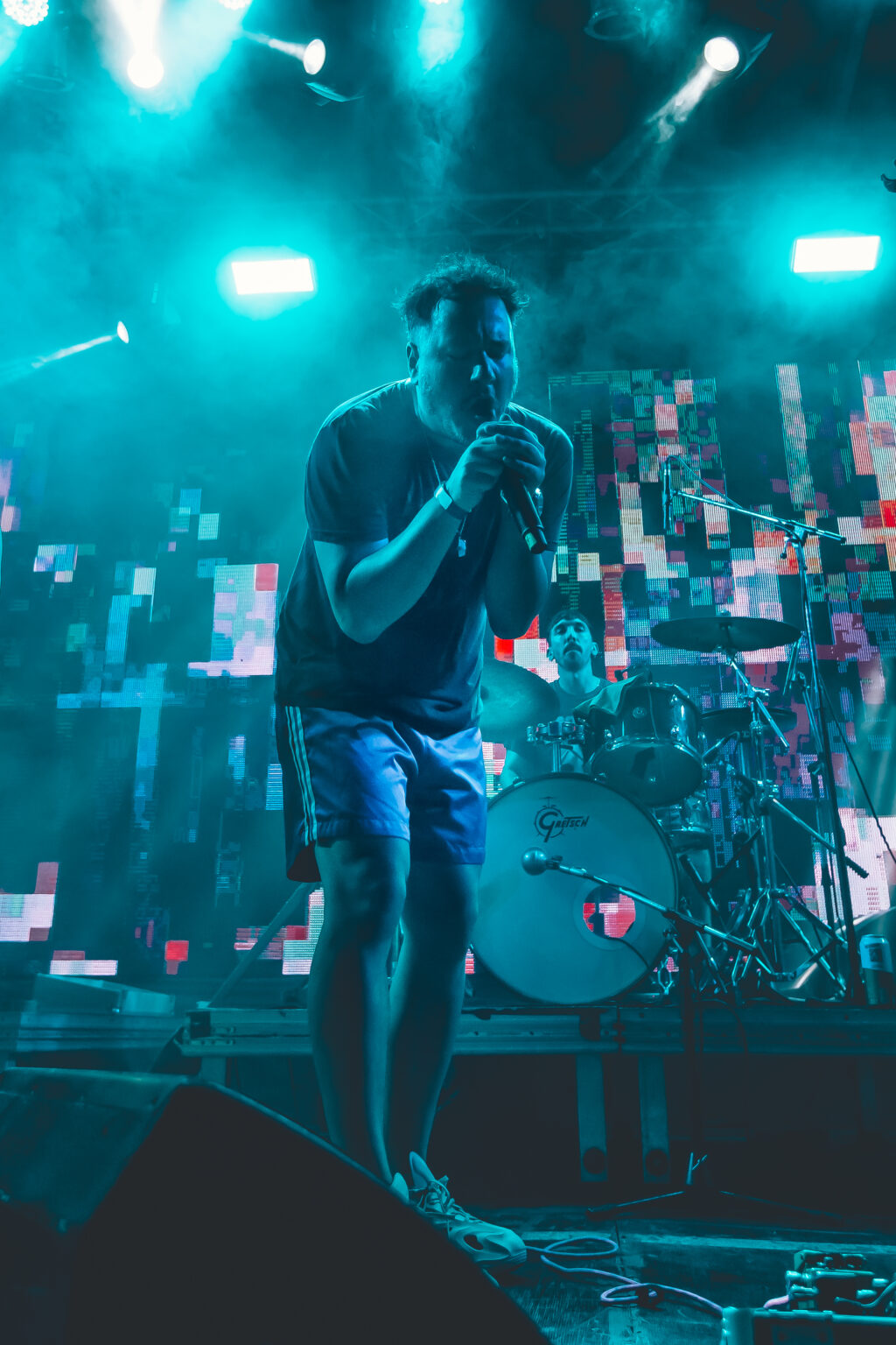 A frontman mid-stride across the stage in blue light &mdash; FestiLaptra at Ciudad Cultural Konex, Buenos Aires, 17 February 2024. Photographed by Anita Almaraz.