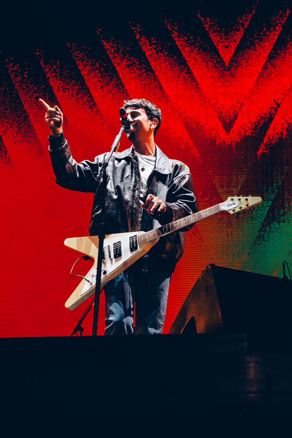 Conociendo Rusia playing guitar against the red backdrop — Festival Buena Vibra, Ciudad Universitaria, Buenos Aires, 2024. Photographed by Anita Almaraz.