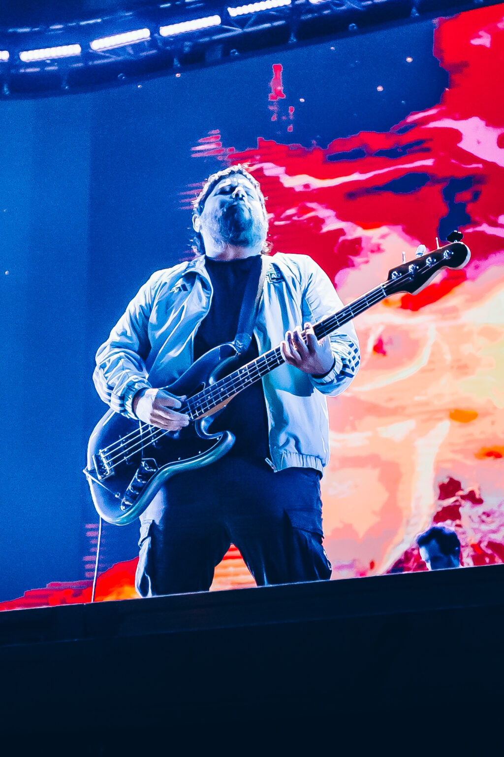 Bass player against the red and blue screen — Festival Buena Vibra, Ciudad Universitaria, Buenos Aires, 2024. Photographed by Anita Almaraz.
