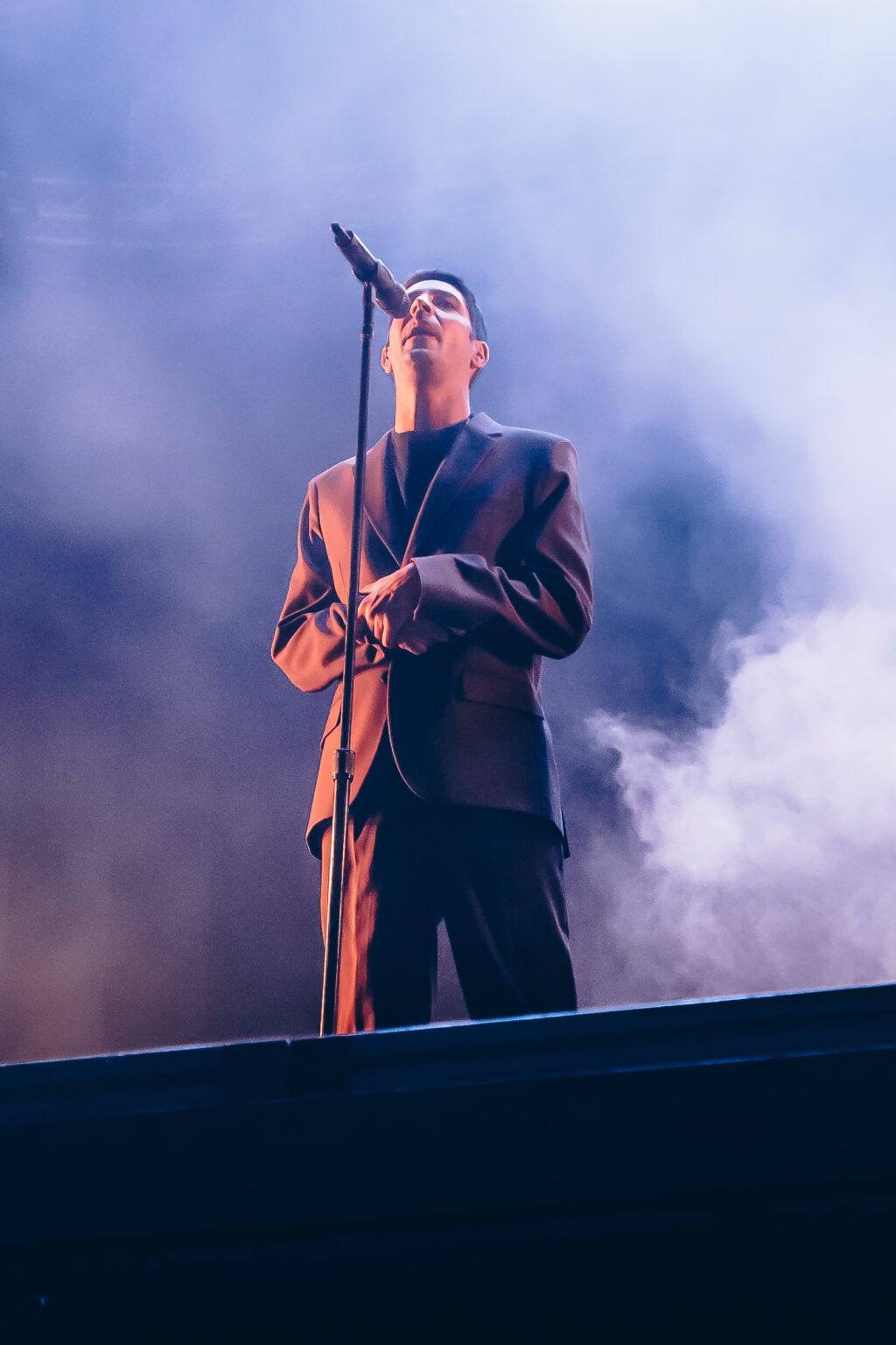 A performer in a brown suit standing in the smoke — Festival Buena Vibra, Ciudad Universitaria, Buenos Aires, 2024. Photographed by Anita Almaraz.