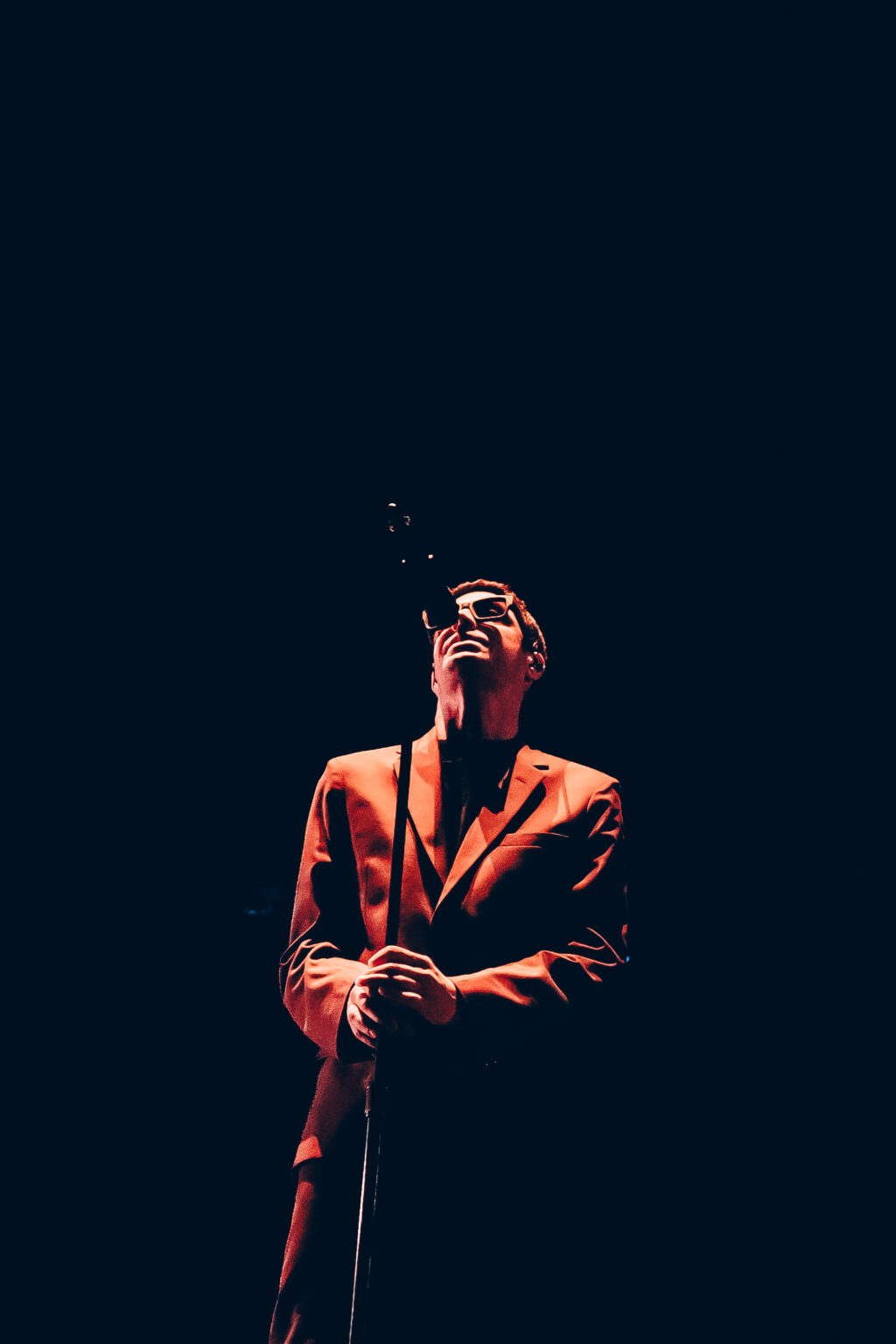 A performer in a brown suit lit from the side — Festival Buena Vibra, Ciudad Universitaria, Buenos Aires, 2024. Photographed by Anita Almaraz.