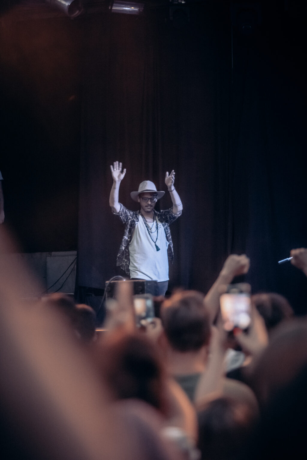 The artist greeting the audience with both hands raised, seen over the crowd — Lisandro Aristimuño at Ciudad Cultural Konex, Buenos Aires, 11 December 2021. Photographed by Anita Almaraz.