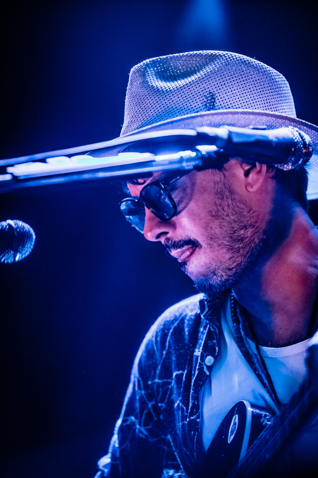 Close portrait of the artist in a hat and sunglasses at the microphone — Lisandro Aristimuño at Ciudad Cultural Konex, Buenos Aires, 11 December 2021. Photographed by Anita Almaraz.