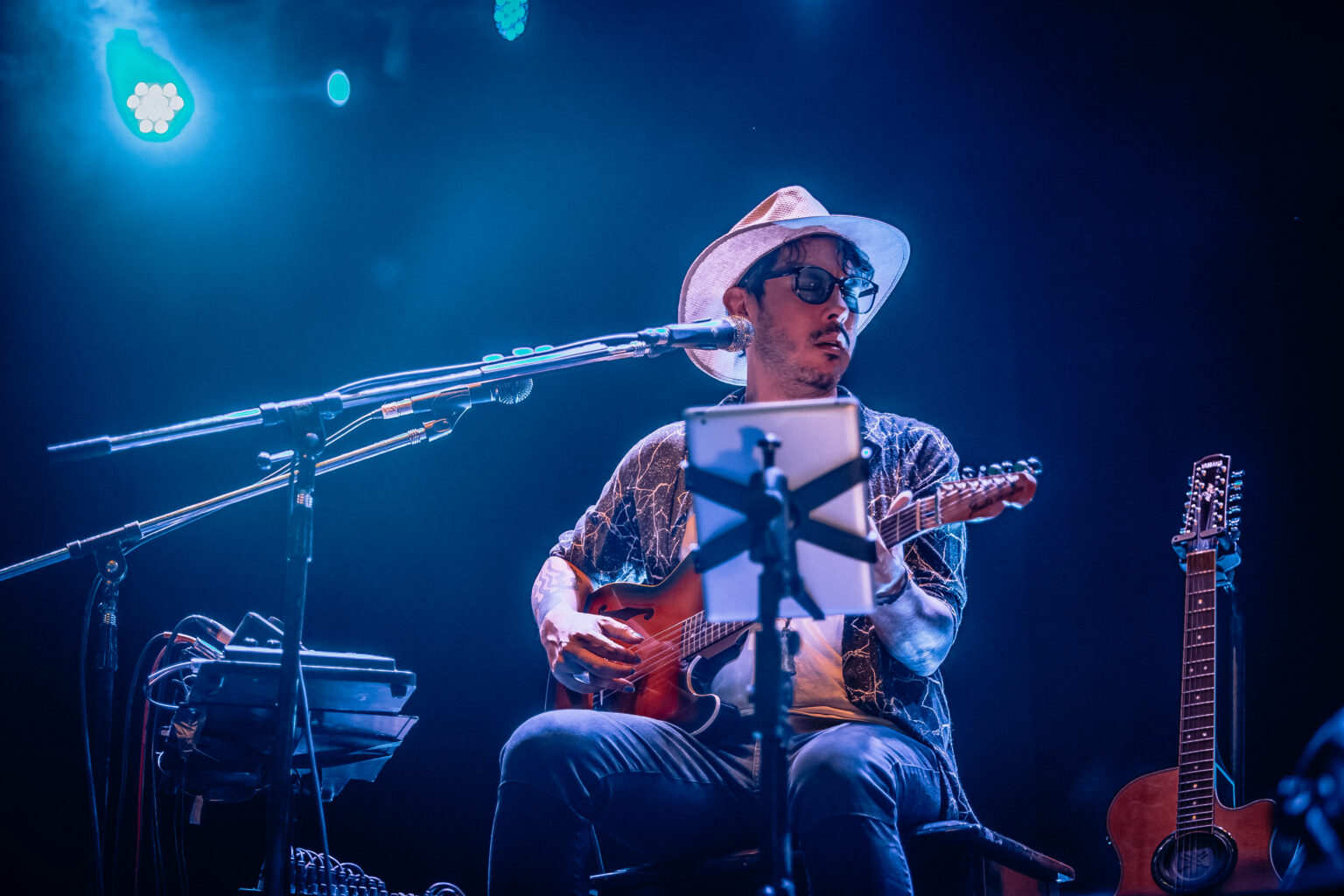 Wide view of the artist seated among the guitars — Lisandro Aristimuño at Ciudad Cultural Konex, Buenos Aires, 11 December 2021. Photographed by Anita Almaraz.