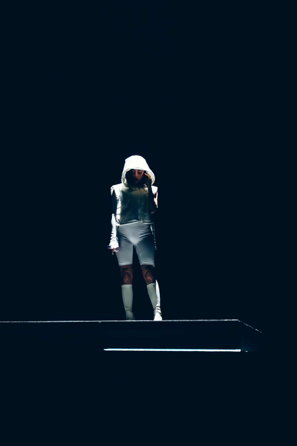 Nicki Nicole alone on the runway of the darkened stage — Movistar Arena, Buenos Aires, August 2023. Photographed by Anita Almaraz for Agencia Télam.