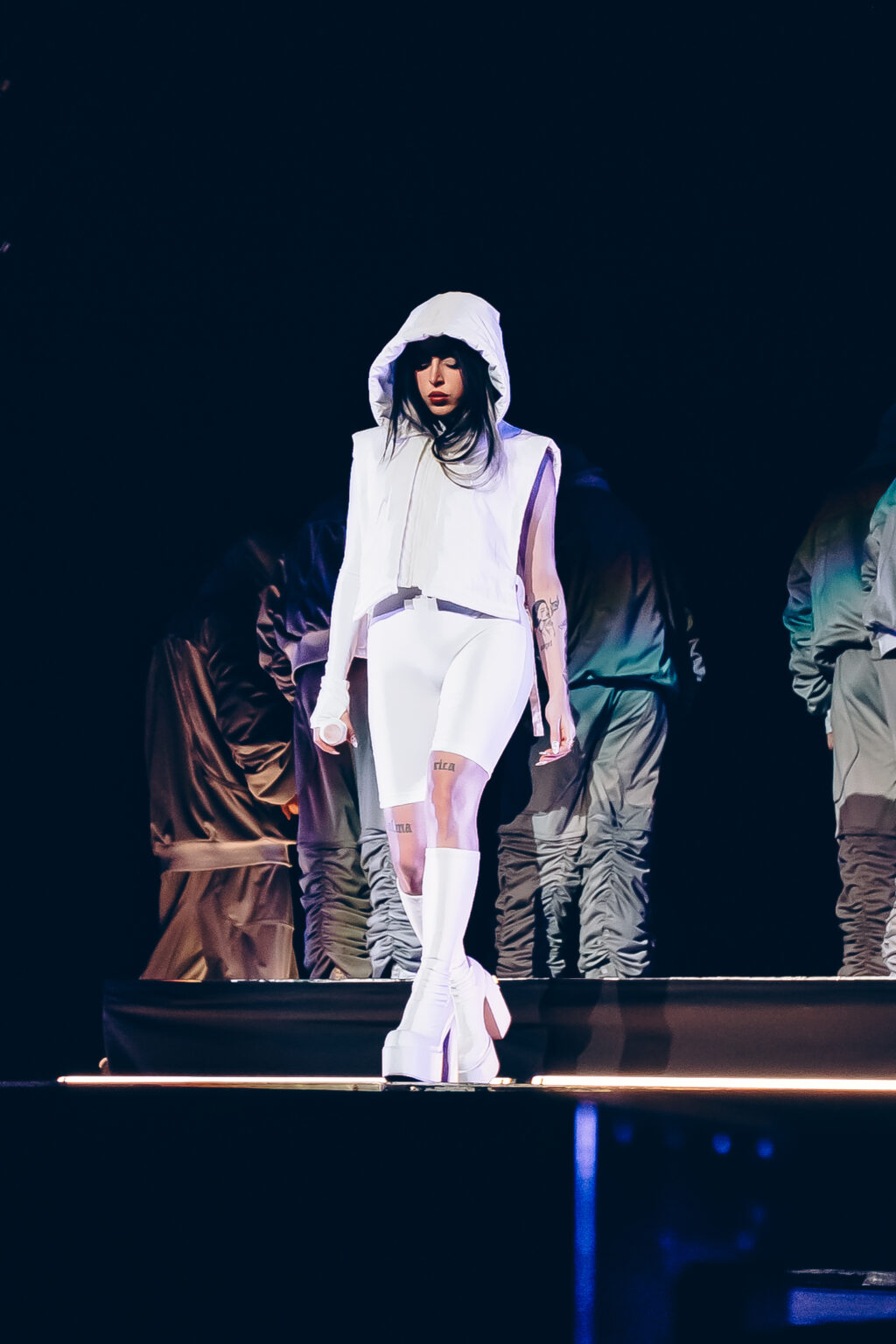 Nicki Nicole walking the stage in a white hooded outfit with her dancers behind — Movistar Arena, Buenos Aires, August 2023. Photographed by Anita Almaraz for Agencia Télam.