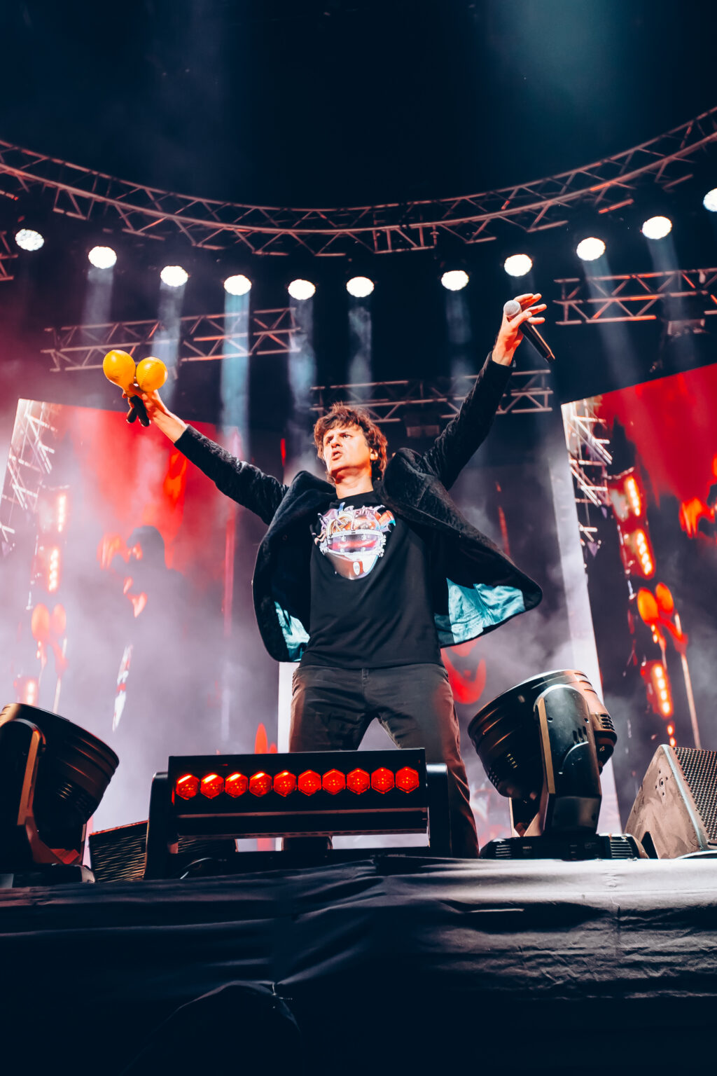 Singer with both arms raised in front of the red banner — Ciro y los Persas at Estadio José Amalfitani, Vélez Sarsfield, Buenos Aires, 9 September 2023. Photographed by Anita Almaraz.