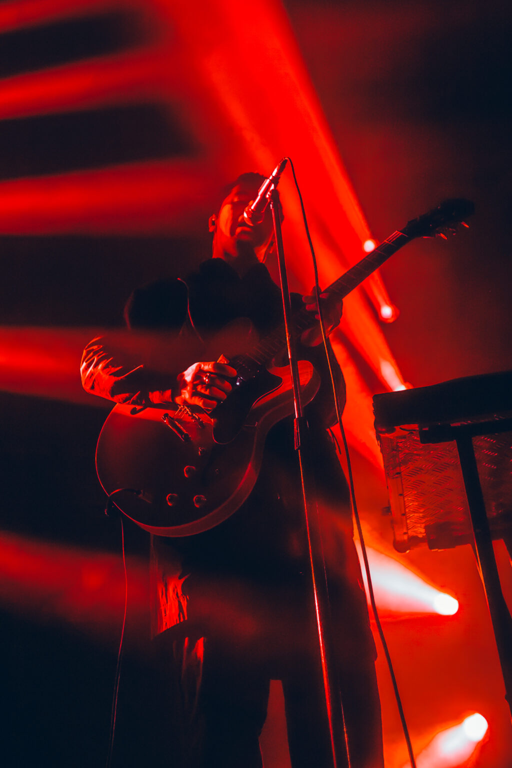 Drums and guitar under red stage light — Peces Raros at Estadio Obras Sanitarias, Buenos Aires, 7 October 2023. Photographed by Anita Almaraz.