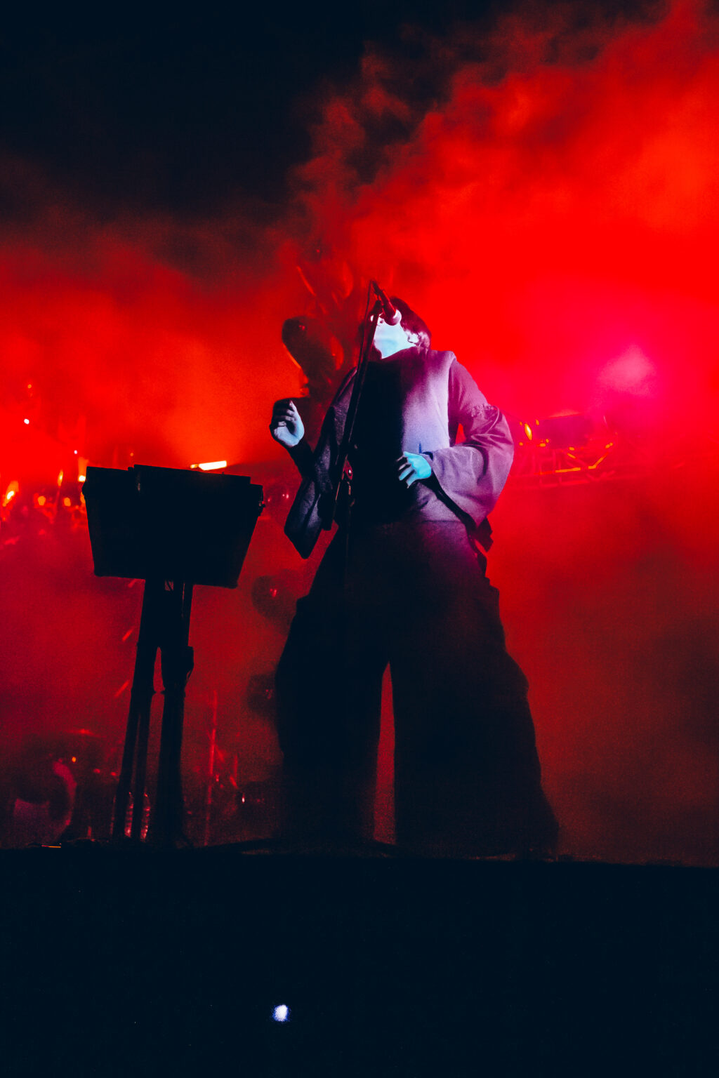 Singer in red smoke behind the keyboards — Peces Raros at Estadio Obras Sanitarias, Buenos Aires, 7 October 2023. Photographed by Anita Almaraz.