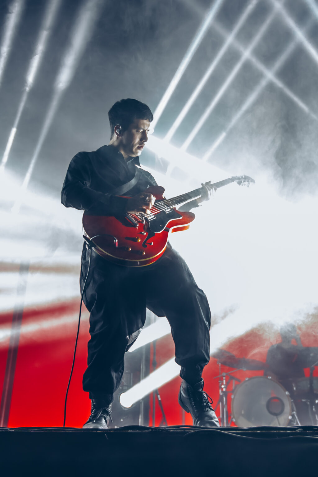 Guitarist with a red guitar against white beams — Peces Raros at Estadio Obras Sanitarias, Buenos Aires, 7 October 2023. Photographed by Anita Almaraz.