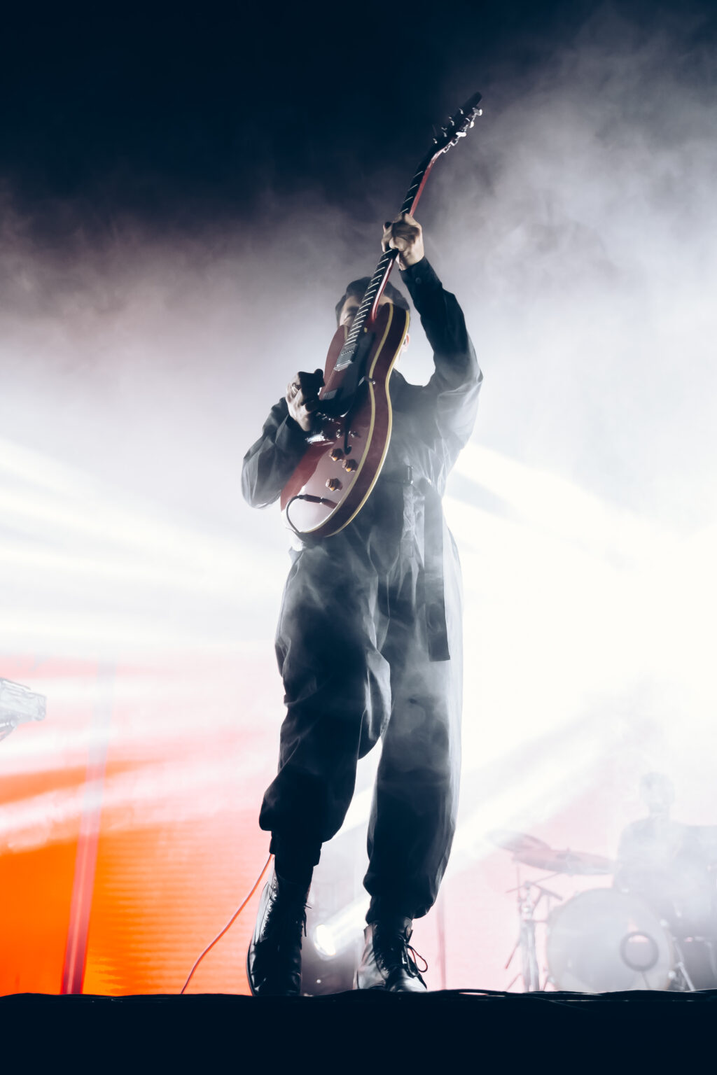 Guitarist leaning back under orange light — Peces Raros at Estadio Obras Sanitarias, Buenos Aires, 7 October 2023. Photographed by Anita Almaraz.