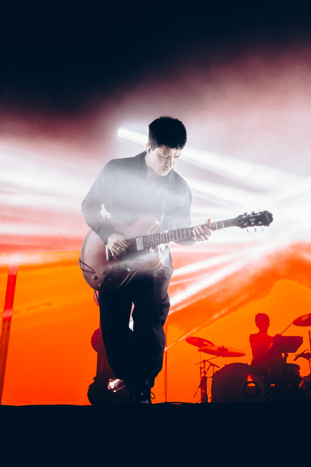 Guitarist against an orange wall of light — Peces Raros at Estadio Obras Sanitarias, Buenos Aires, 7 October 2023. Photographed by Anita Almaraz.