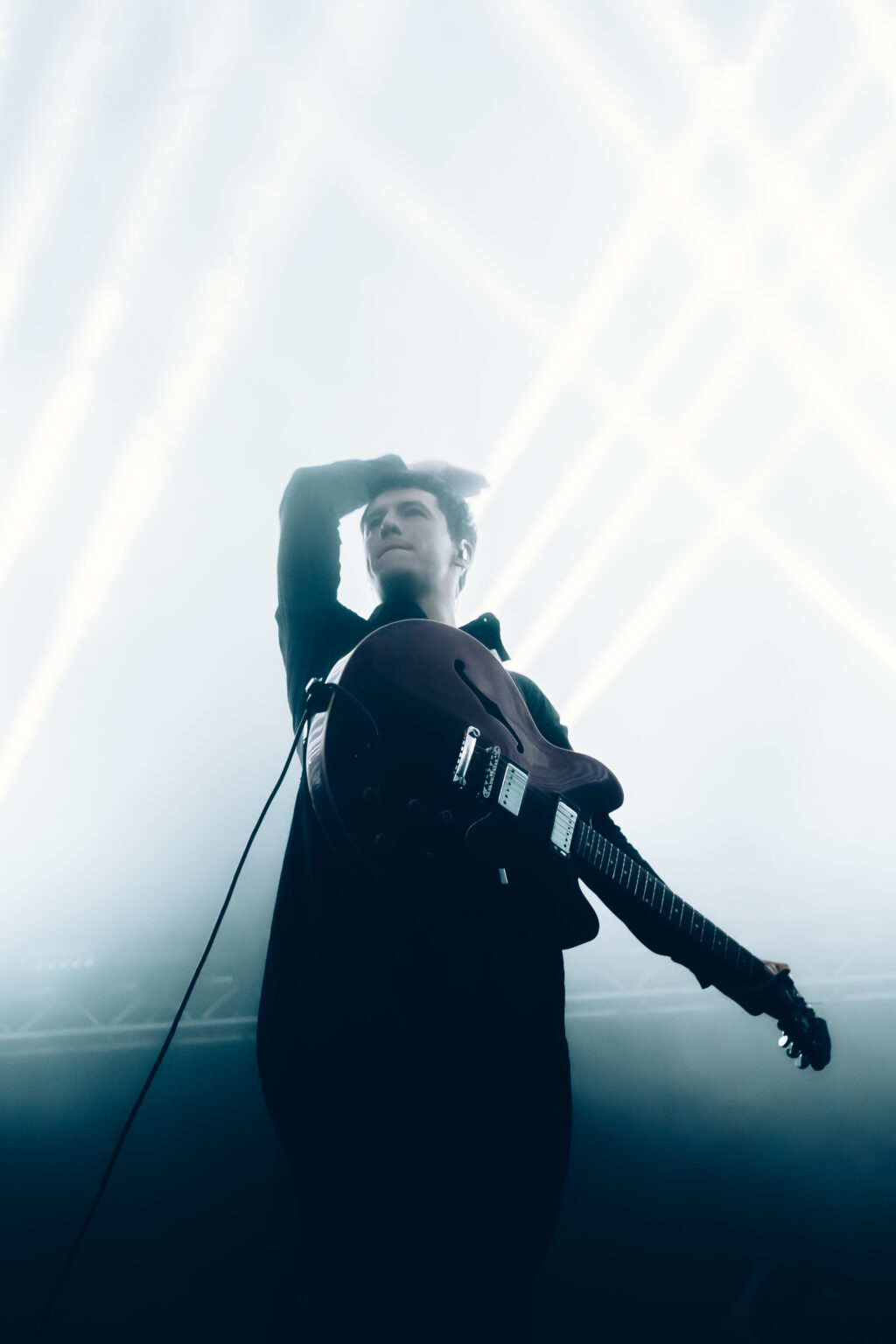 Singer with an arm over the head in the white haze — Peces Raros at Estadio Obras Sanitarias, Buenos Aires, 7 October 2023. Photographed by Anita Almaraz.
