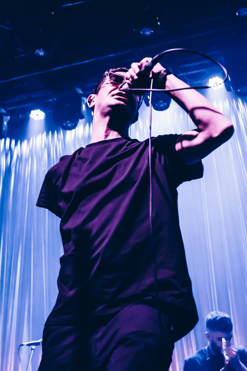 Singer raising a phone above his head — El Kuelgue at C Complejo Art Media, Buenos Aires, 23 November 2023. Photographed by Anita Almaraz.
