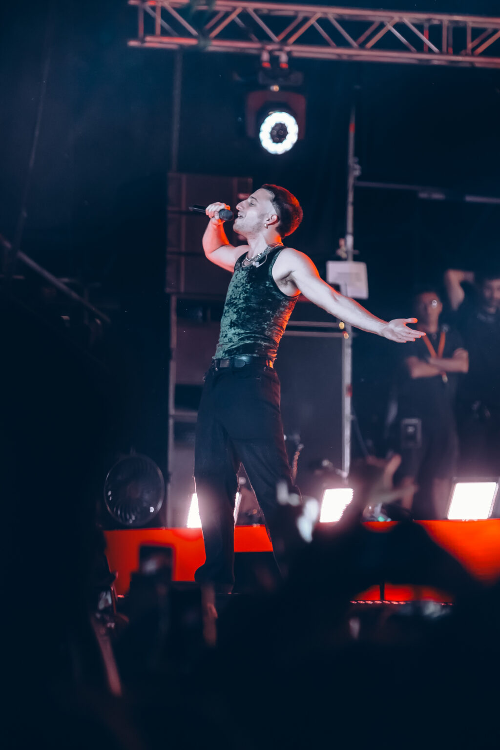 Wos with his arm raised in the orange stage smoke — Wos live in Buenos Aires, photographed by Anita Almaraz.