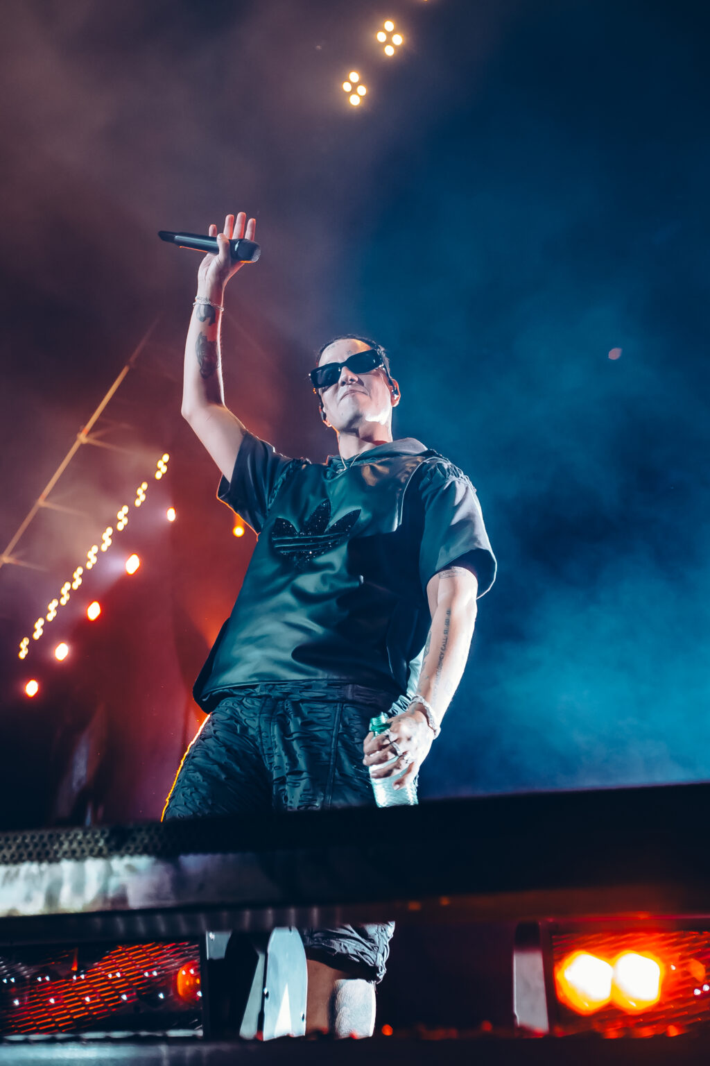 Duki with an arm raised under the lighting rig — Duki at Estadio River Plate, Buenos Aires, 2 December 2023. Photographed by Anita Almaraz.