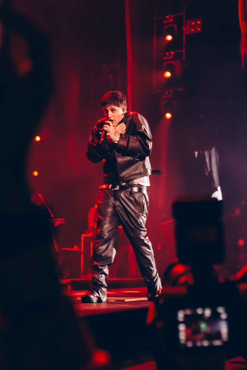 Dillom lit in deep red with the crew around him — Dillom at Estadio Luna Park, Buenos Aires, 19 June 2024. Photographed by Anita Almaraz.