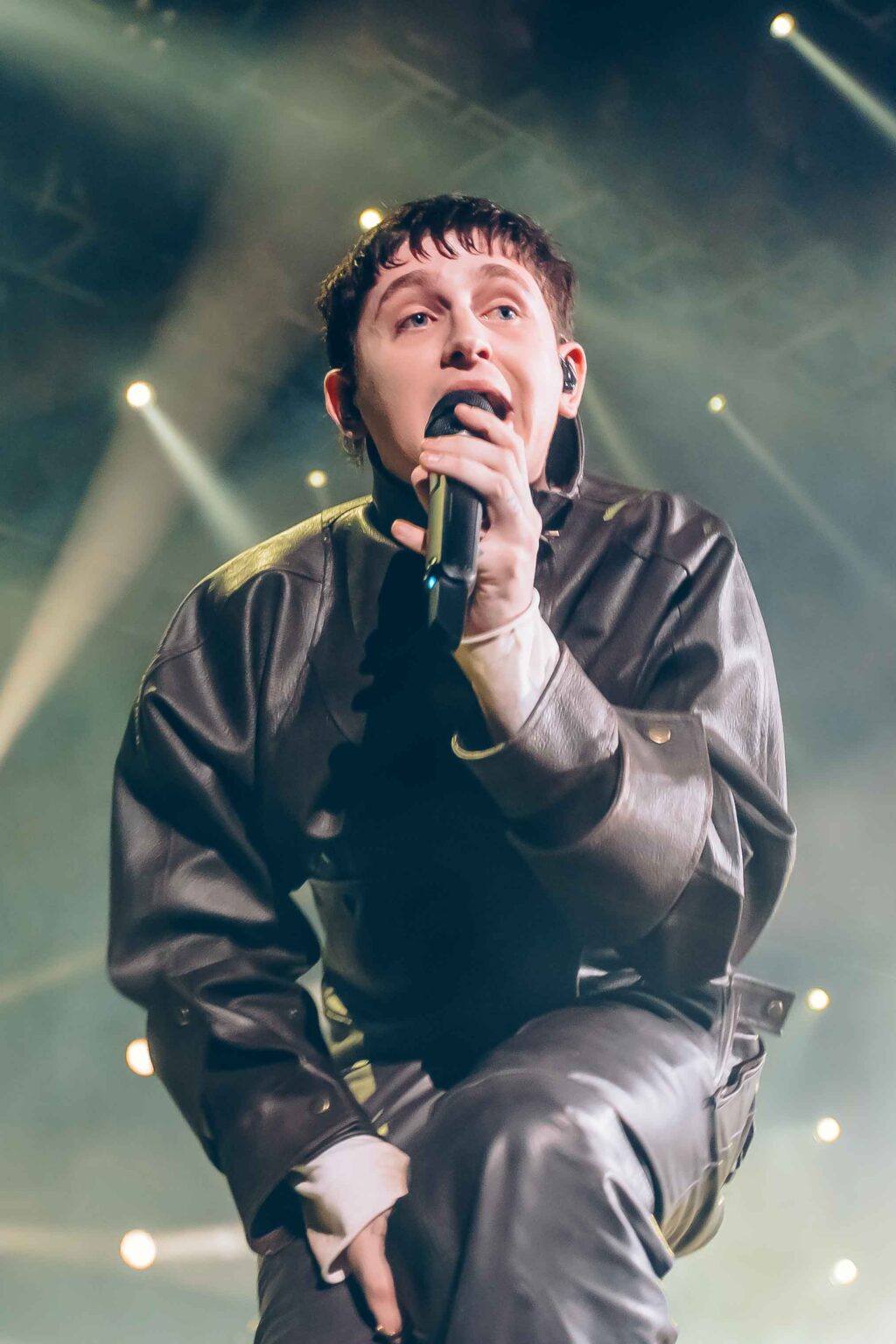 Close portrait of Dillom kneeling and shouting into the mic — Dillom at Estadio Luna Park, Buenos Aires, 19 June 2024. Photographed by Anita Almaraz.