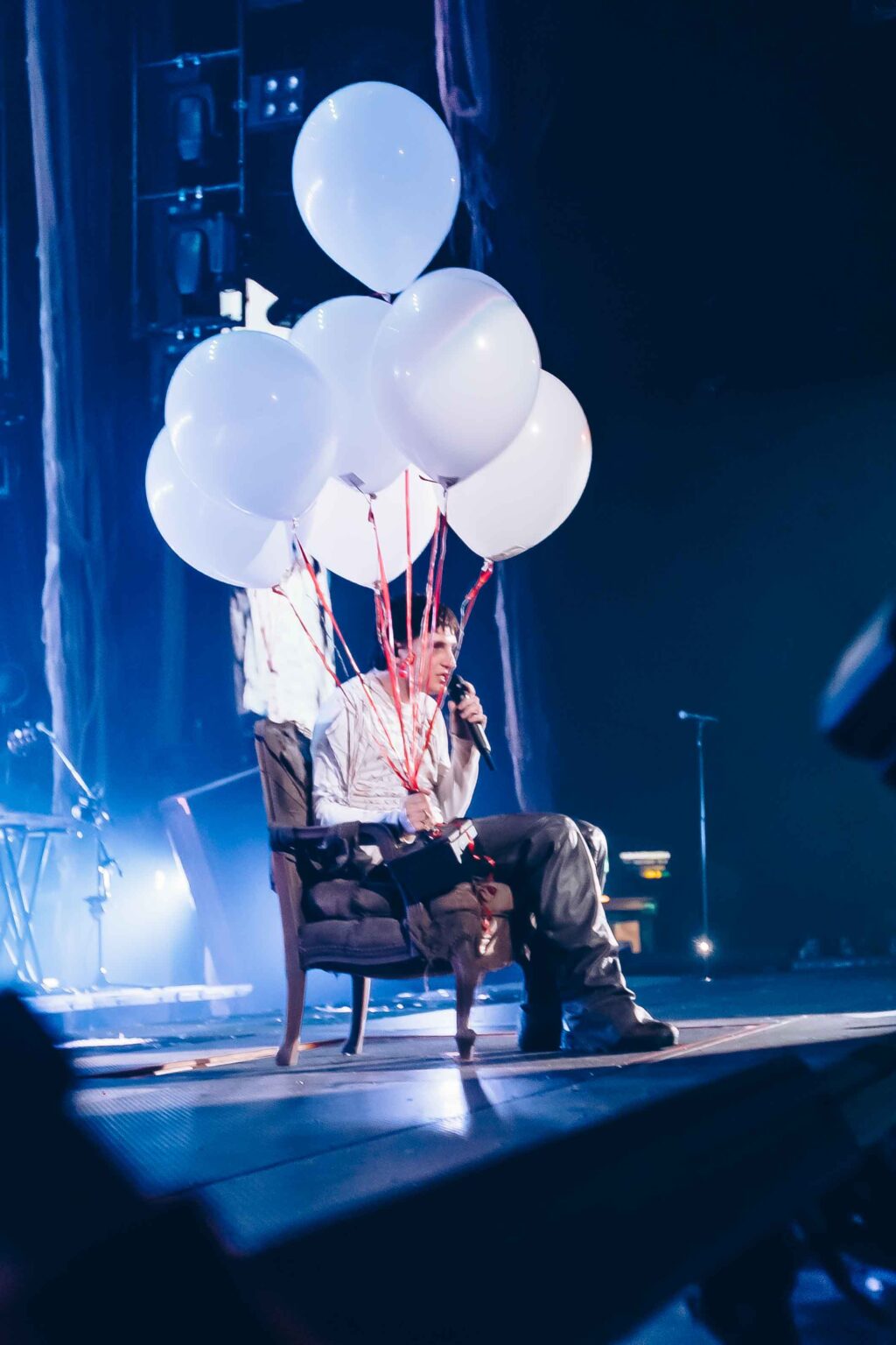 Dillom sitting in a chair with the balloons above him — Dillom at Estadio Luna Park, Buenos Aires, 19 June 2024. Photographed by Anita Almaraz.
