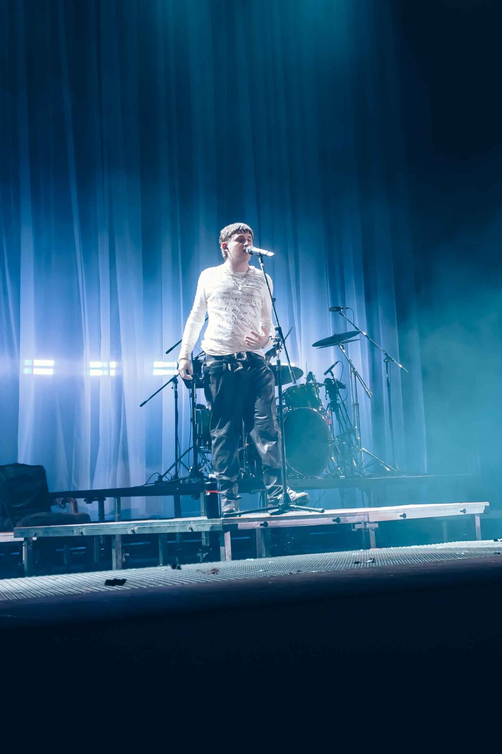 A performer lying on the table in the blue light — Dillom at Estadio Luna Park, Buenos Aires, 19 June 2024. Photographed by Anita Almaraz.